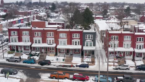 Aerial-of-colorful-row-houses-covered-in-snow,-decorated-for-holidays