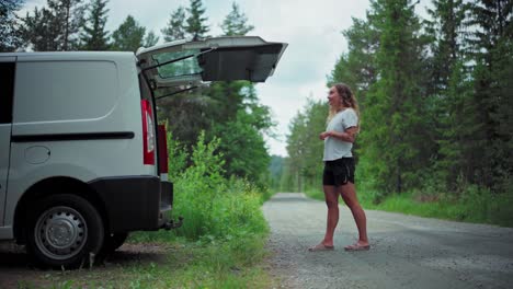 Caucasian-Woman-Opens-Tailgate-Of-A-White-Van-Parked-In-A-Rural-Area