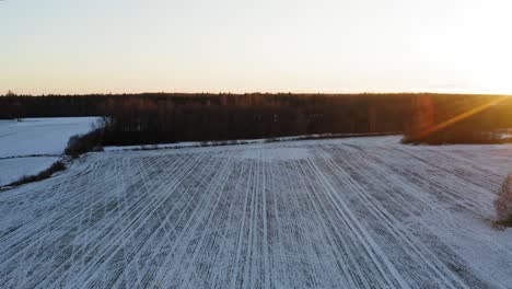 Sunset-Over-Snowy-Field-With-Tracks-In-Winter