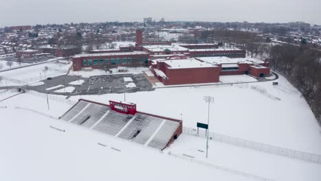 Aerial-of-school-college-university-campus-athletic-fields-covered-in-winter-snow