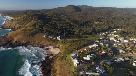 Wide-drone-shot-of-Scotts-Head-mountain-landscape,-beach-and-town-in-Australia