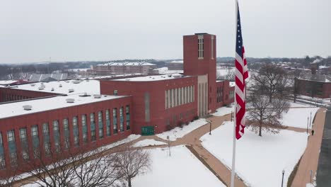 Aerial-establishing-shot-of-large-brick-school-building-covered-in-snow-during-winter