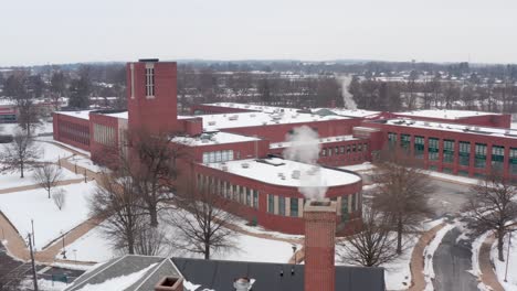 Aerial-reveal-of-large-school,-college,-university-building-during-winter-snow