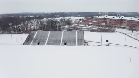Aerial-of-school-athletic-fields-and-bleachers-covered-in-winter-snow