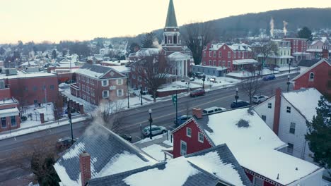 Aerial-tilt-up-reveals-homes-and-church-in-small-town-community-covered-in-winter-snow