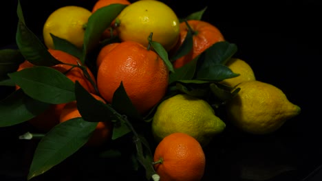 Frutas-Cítricas,-Limones-Amarillos-Y-Mandarinas-Naranjas-Girando-Sobre-Fondo-Negro,-Comida-Saludable