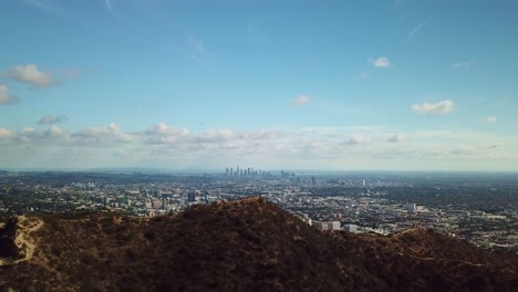 Wide-aerial-shot-of-Downtown-Los-Angeles-with-hikers-on-mountain-in-the-foreground