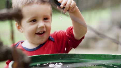 Smiling-white-boy-child-dropping-toy-plane-into-a-barrel-full-of-water,-SLOW-MOTION