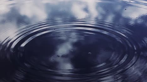 Water-drops-falling-into-perfect-lake-reflection-creating-beautiful-small-waves