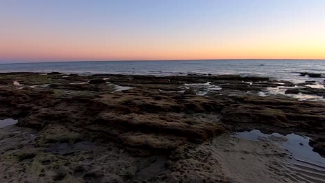 Sea-birds-fly-by-in-the-distance-as-the-sunsets-on-the-tide-pools-of-Rocky-Point,-Mexico
