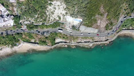 Hong-Kong-bay-coastal-road-with-traffic-and-calm-turquoise-water,-Aerial-view
