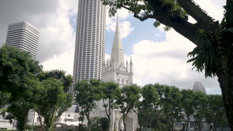 Vista-De-La-Catedral-De-St-Andrews-En-Singapur-Con-La-Torre-De-La-Ciudad-De-Raffles-En-El-Fondo---Inclinación-Hacia-Arriba