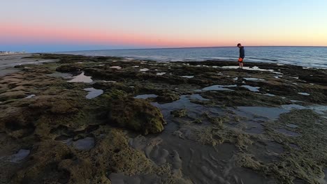A-man-with-an-Orange-Frisbee-navigates-across-the-tide-pools-left-after-the-tide-has-gone-out,-Puerto-Peñasco,-Gulf-of-California,-Mexico