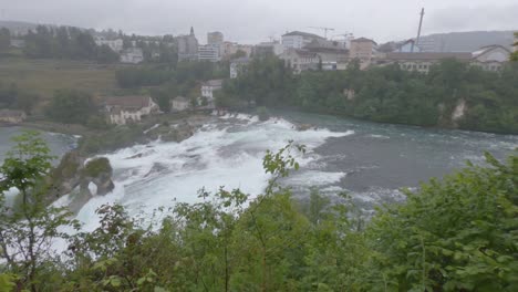 Rhine-Falls-on-rainy-day-and-town-panorama,-rapid-river,-waterfall