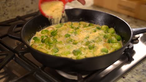 Cooking-Roasted-Sautéed-Brussels-Sprouts-in-a-Cast-Iron-Pan-Skillet---Sprinkling-Parmesan-out-of-Measuring-Cup