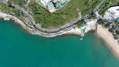Hong-Kong-bay-coastal-road-with-traffic-and-calm-turquoise-water,-Aerial-view