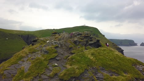 Wanderer,-Der-Auf-Die-Spitze-Der-Felsigen-Küstenklippe-In-Cornwall,-Großbritannien,-Klettert,-Luftbild