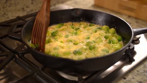 Cooking-Roasted-Sautéed-Brussels-Sprouts-in-a-Cast-Iron-Pan-Skillet---Stirring-in-Parmesan-with-a-Wooden-Spatula