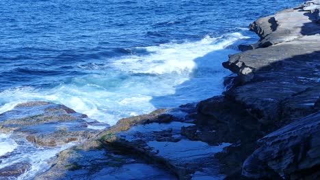 Scenery-Of-Crashing-Waves-Against-Rocky-Coastal-Hills-During-Sunny-Day