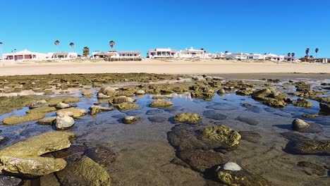 Pan-left-across-the-tide-pools-left-on-the-beach-after-the-tide-goes-out,-Puerto-Peñasco,-Gulf-of-California,-Mexico