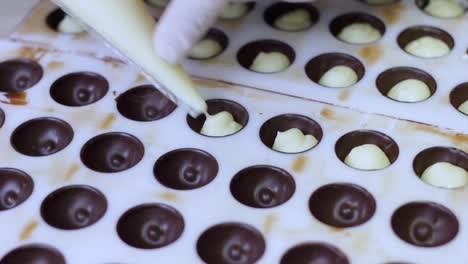 Chocolatier-Pouring-ganache-filling-Into-Chocolate-Mold-Preparing-Candy
with-a-pastry-bag