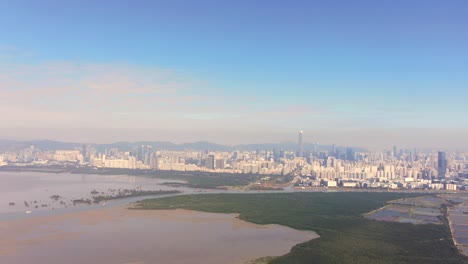 Hong-Kong-and-Shenzhen-border-line-over-Hong-Kong-rural-houses-with-Shenhzen-skyline-in-the-horizon,-Aerial-view