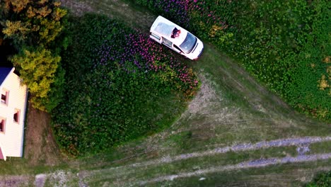 Top-View-Of-Romantic-Couple-Relaxing-On-The-Roof-Of-A-Camper-Van-In-A-Floral-Park