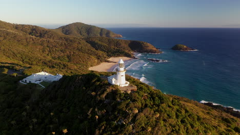 Wide-cinematic-drone-shot-rotating-around-Smoky-Cape-Lighthouse-in-Australia-revealing-Green-Island,-the-Ledge-and-the-Pacific-ocean