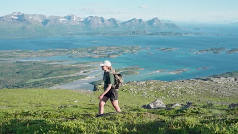 Female-Hiker-Crossing-The-Meadow-With-View-Of-The-Ocean-In-Norway