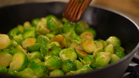 Cooking-Roasted-Sautéed-Brussels-Sprouts-in-a-Cast-Iron-Pan-Skillet---Stirring-in-Parmesan-with-a-Wooden-Spatula---Close-Up-Macro-Shot