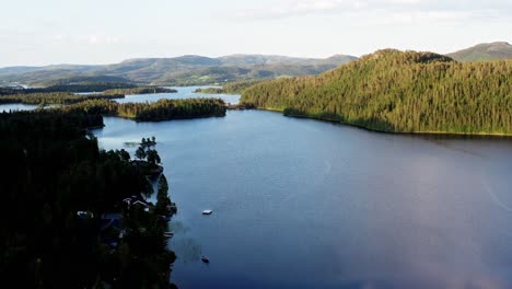 Drohne,-Die-Im-Sommer-In-Norwegen-In-Richtung-Eines-Ruhigen-Ozeans-Mit-Nadelbergen-Im-Hintergrund-Fliegt