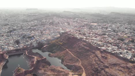 Ranisar-Padamsar-Lakes-near-Mehrangarh-Fort-and-bordering-the-blue-city-of-Jodhpur,-Rajasthan,-India---Aerial-slow-panoramic-shot