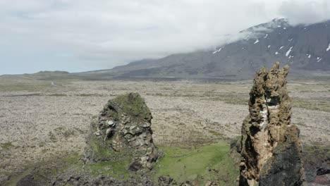 Volcanic-basalt-towers-on-shore-of-iceland-with-large-mountain-in-background