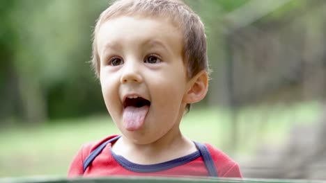 Young-caucasian-boy-making-funny-faces-and-sticking-his-tongue-out,-SLOW-MOTION