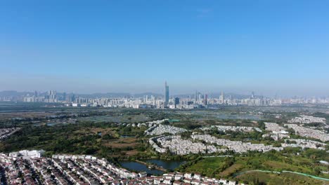 Hong-Kong-and-Shenzhen-border-line-over-Hong-Kong-rural-houses-with-Shenhzen-skyline-in-the-horizon,-Aerial-view