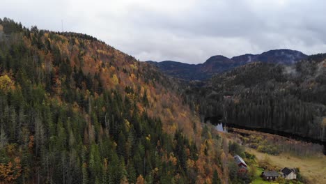 Scenic-drone-footage-of-a-mountain-cottages,-forest-river-and-hills-in-Autumn