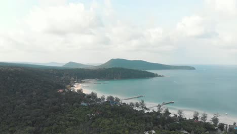 Exotic-Paradisiac-landscape-bordering-the-calm-turquoise-ocean-in-Saracen-Bay,-Koh-Rong-Sanloem,-Cambodia---Aerial-Wide-establishing-Fly-over