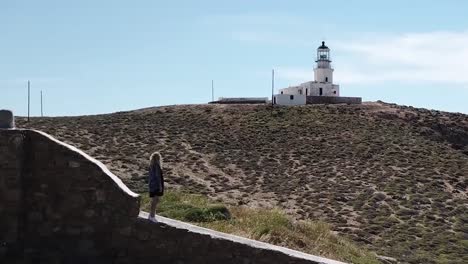 Aerial-Drone-On-Woman-Standing-In-Front-Of-Lighthouse-Parallax
