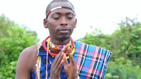 Maasai-male-fixing-his-traditional-attire-and-greets-to-a-camera