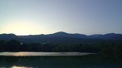 Ang-Kaew-lake-at-Chiang-Mai-University-with-forested-mountain-and-twilight-sky