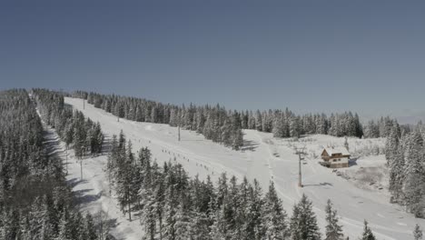Skiers-going-downhill-on-Kope-ski-resort-in-Pohorje-mountains-Slovenia,-Aerial-hovering-shot