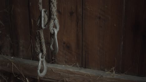 Farm-slip-or-lifting-hooks-on-rope-against-a-wooden-wall,-medium-shot