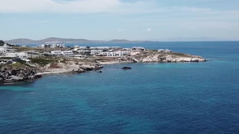 Drone-Aéreo-Avanzando-En-La-Playa-Azul-De-Mykonos