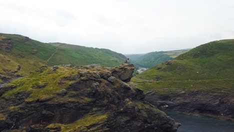 Hikers-on-Cornwall-clifftop,-United-Kingdom-coastline,-aerial-arc-shot