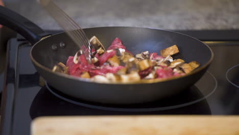 Slow-motion-cooking-mushrooms-and-steak-in-a-skillet
