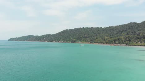 Shoreline-green-hills-circling-around-calm-turquoise-waters-in-Saracen-Bay-in-Koh-Rong-Sanloem,-Cambodia---Aerial-Panoramic-shot