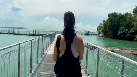Woman-Traveler-Walking-Across-Coastal-Boardwalk-At-Chek-Jawa-Wetlands-In-Pulau-Ubin-Island,-Singapore