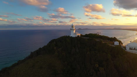 Filmische-Rotierende-Sonnenaufgangsdrohnenaufnahme-Des-Rauchigen-Kap-leuchtturms-In-Der-Nähe-Von-Südwestfelsen,-Kempsey-Shire,-New-South-Wales,-Australien