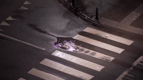 Heavy-rainfall-forms-a-puddle-of-water-on-the-crosswalk-in-the-street-at-night