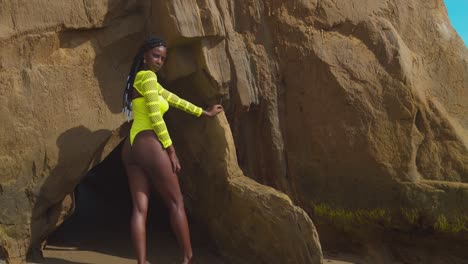 Pretty-African-Queen-stands-at-the-entrance-to-a-cave-in-a-yellow-sexy-bikini